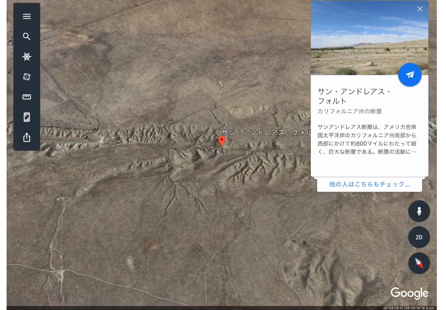 カリフォルニアのサン・アンドレアス断層を上空から見た衛星画像。乾いた土地を左右に横切る直線的な地形の筋が走り、その上に赤いピンと「サン・アンドレアス・フォルト」のラベル、右側に断層の解説カードが開いている。